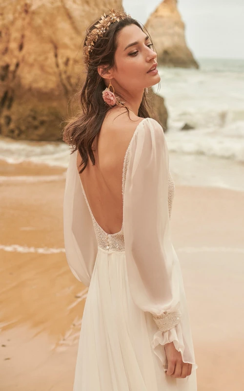 Vestido de novia informal de gasa con escote pronunciado, mangas largas abullonadas y corte imperio, con top de cuentas.